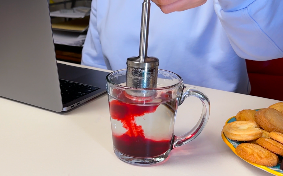FinalPress stainless steel brewer stirring red hibiscus tea drink in glass mug