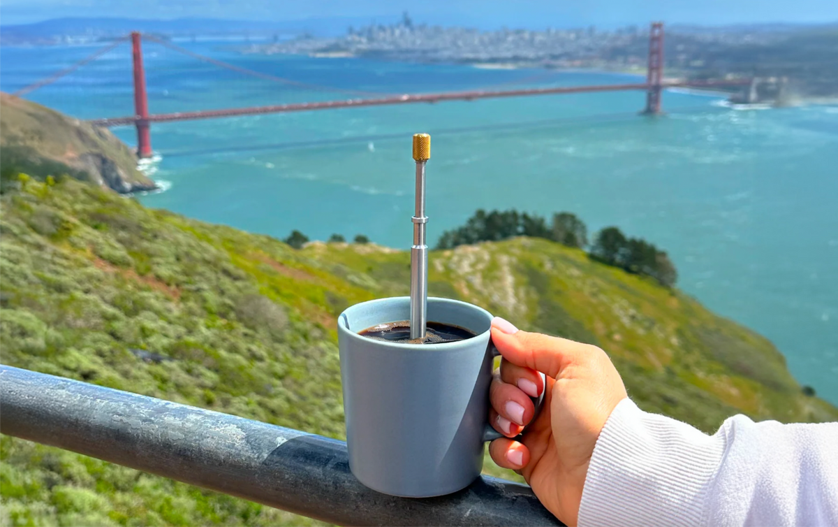 FinalPress portable coffee brewer in mug held by hand overlooking Golden Gate Bridge